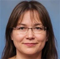 A professional woman with glasses smiling warmly for a testimonial.