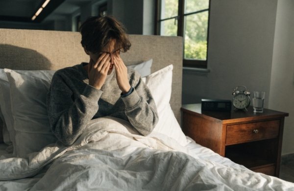 Tired and groggy person waking up in the morning after sleeping with LED strip lights on