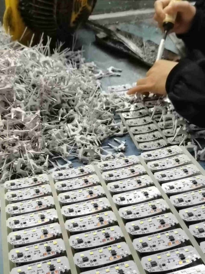 Worker assembling night light circuit boards on a production line.